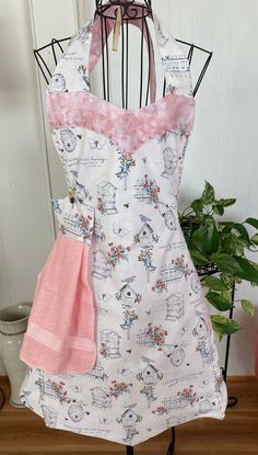 a white apron with pink flowers on it and a pink towel hanging from the front