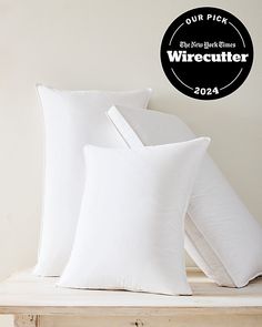 three white pillows sitting on top of a wooden table next to a black and white sign