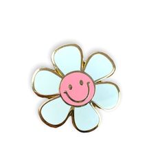 a pink and blue flower with a smiley face on it's center, sitting in front of a white background