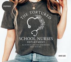 a woman wearing a t - shirt that says the tortured school nurses department all's fair in love and sending kids back to class