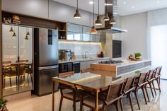 a modern kitchen with stainless steel appliances and wooden dining chairs, along with an island