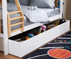 a white bunk bed with drawers underneath it and a rug on the floor next to it