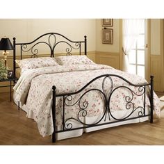 a bed that has a metal frame and floral bedspread on top of it