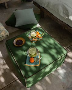 a table with plates and bowls on it in front of a green blanketed bed