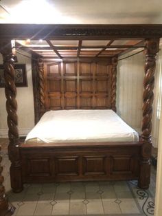 a wooden bed frame with white sheets and pillows on top of it in a room