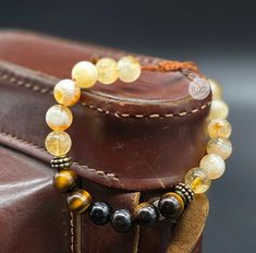 Harmonize your energy with this exquisite unisex chakra bracelet, featuring 8mm natural Citrine, Tiger's Eye, and Obsidian stones. Designed to fit a 17 cm wrist, this bracelet is equipped with a sliding closure for easy adjustment and is finished with a 4mm Tiger's Eye accent on the clasp, blending elegance with powerful spiritual properties. Citrine: Citrine, known as the "Stone of Abundance," is believed to attract prosperity, success, and positivity. Its vibrant yellow hue radiates warmth and Spiritual Beaded Bracelets With Sliding Knot, Adjustable Round Crystal Bracelet For Meditation, Adjustable Gemstone Bracelets For Meditation, Adjustable 8mm Beads Crystal Bracelet For Meditation, Adjustable Amber Gemstone Bead Bracelets, Adjustable Amber Gemstone Beads Bracelet, Adjustable Gemstone Beaded Bracelets For Meditation, Adjustable Gemstone Crystal Bracelet For Meditation, Adjustable Amber Crystal Bracelet With Gemstone Beads