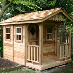 a small wooden shed sitting on top of a lush green field next to a tree