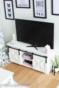 a flat screen tv sitting on top of a white entertainment center next to a christmas tree