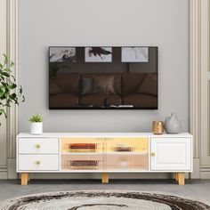 a living room with a large flat screen tv mounted on the wall above a white entertainment center