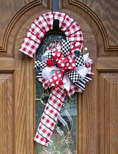 a red and white checkered wreath on a wooden door with the words welcome home