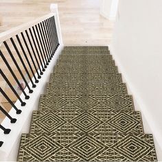 a stair mat on the bottom of a set of stairs with black iron railings