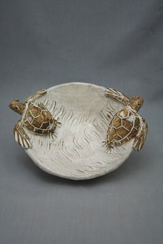 two small turtles sitting on top of a white bowl