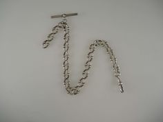 The chain is made of Continental silver; this is a lower grade of silver than English silver and so consequently it doesn't have any silver hallmarks, , just marked SS - Sterling silver. The chain measures 290mm in length from the T bar to the dog clip. This fancy watch chain is made up of oval links with ball motifs. Hanging from the T bar there is an additional length of curb links from which you could hang a fob or accessory. The chain is in 85% mint condition - the ends of the links are worn Silver Metal Chain Necklace With Wheat Chain, Victorian Link Necklace Hallmarked, Silver Sterling Wheat Chain Bracelet, Victorian Hallmarked Link Necklace, Formal Sterling Silver Link Bracelet With Curb Chain, Formal Hallmarked Chain Link Necklace, Silver Double Chain Link Bracelet, Classic Silver Wheat Chain Bracelet, Victorian Curb Chain Necklaces