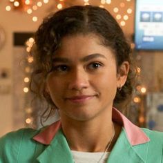 a woman with curly hair wearing a green jacket