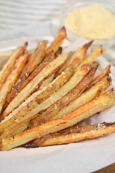 some french fries are on a plate with dipping sauces in the bowl behind them