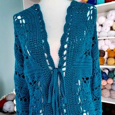 a blue crocheted sweater is displayed on a mannequin