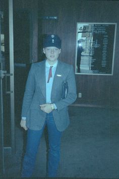 a woman standing in an elevator wearing a suit and tie with a hat on her head