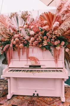 a pink piano with flowers and feathers on it