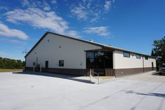 an empty building with a car parked in the lot next to it on a sunny day