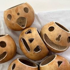 five wooden masks with faces on them sitting on a white cloth covered tablecloth in the shape of smiley faces