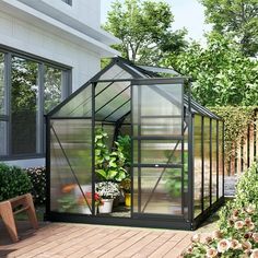 a small green house sitting on top of a wooden deck