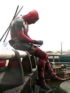 a man dressed in deadpool sitting on the edge of a boat looking at something