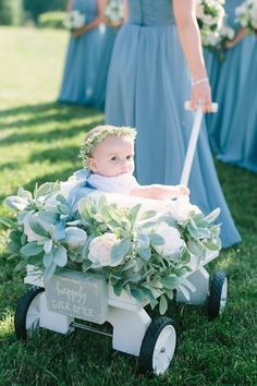 a baby sitting in a wagon with flowers on it