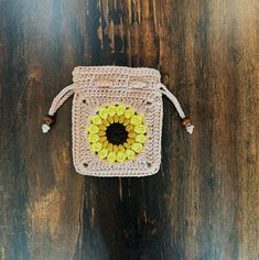 a small crocheted bag with a sunflower on the front and side, sitting on a wooden surface