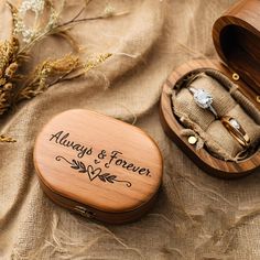 two wedding rings in a wooden box on a table next to some dried plants and flowers