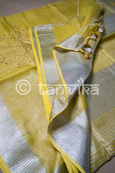 This elegant tissue linen drape in a beautiful gold tone features the beautiful and meticulously done floral cutwork design. This saree has pretty faux mirror (flattened sequin discs) work which adds a lovely vibe and bling to the whole outfit. The saree might have slight irregularities in the pattern & colors, which results from the human involvement in the process & is a hallmark of handcrafted products. Minor thread pulls are not considered damage. We recommend professional dry cleani Gold Slub Silk Dupatta With Resham Embroidery, Gold Tissue Silk Kurta With Zari Work, Gold Dupatta With Resham Embroidery In Slub Silk, Gold Slub Silk Kurta For Festivals, Elegant Yellow Tussar Silk Traditional Wear, Gold Cotton Silk Saree With Gota Work, Gold Slub Silk Kurta With Cutdana, Elegant Yellow Tussar Silk Blouse Piece, Gold Chanderi Kurta With Cutdana Details