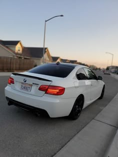 the white car is parked on the side of the road