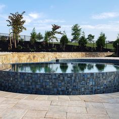 an empty pool surrounded by stone walls and trees in the background with no people around it