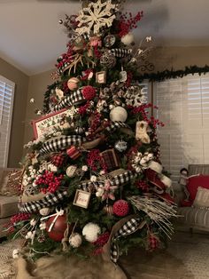 a decorated christmas tree in a living room with red, white and black ornaments on it