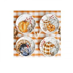 four plates with turkeys and pumpkins on them sitting on a checkered tablecloth