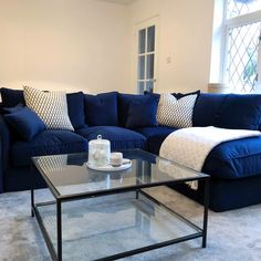 a living room with blue couches and pillows on the floor, coffee table in front of it