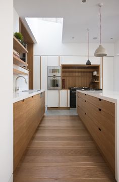 an empty kitchen with wooden floors and white cabinets on either side of the countertop