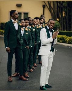 a group of men in green and white tuxedos standing next to each other