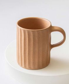 a brown coffee cup sitting on top of a white plate