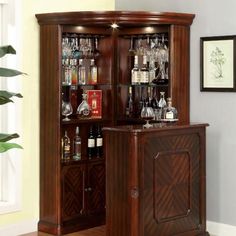 a wooden cabinet with wine glasses and liquor bottles on it's shelves in a living room