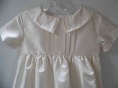 Inspired by a customers wedding gown, This infant baptism, blessing, christening gown is the ultimate in unisex gowns for my shop. The bodice has 6 pleats down the front with a pointed collar that reaches around to the back. The fabric is an off white shantung but can be done in cotton if requested. At 36 inches this is my longest gown and features a straight sleeve, gathered skirt, lining, and buttons in the back. LIMITED QUANTITIES Hat sold separately: https://www.etsy.com/listing/200586726/un Elegant Fitted Gown For Church, Elegant Fitted First Communion Dress For Formal Occasions, Elegant Gown With Fitted Bodice For First Communion, Elegant First Communion Gown With Fitted Bodice, Classic Fitted Dress For Baptism, Elegant Cream First Communion Dress, Elegant Cream Dresses For Church, White Elegant Baptism Dress, Elegant Fitted Gown For Baptism