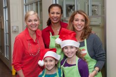 a group of women standing next to each other wearing green aprons and santa hats