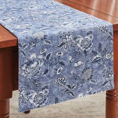 a wooden table with a blue and white floral design on the table cloth over it