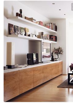 a living room filled with furniture and bookshelves on top of wooden shelves in front of a flat screen tv