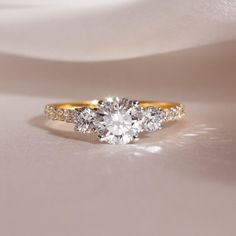 a three stone diamond ring on top of a white cloth