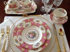 the table is set with pink and gold china