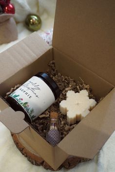 a bottle of wine in a cardboard box on top of a table next to a candle