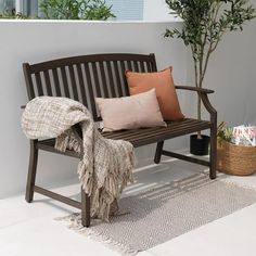 a wooden bench sitting on top of a white floor next to a potted plant