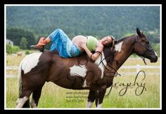 a woman laying on the back of a brown and white horse in a grassy field