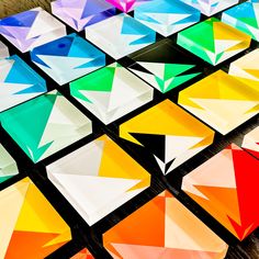 many different colors of paper are arranged on the table together, with one being cut into smaller squares