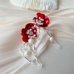 a red flower brooch with pearls on it sitting on top of a white dress